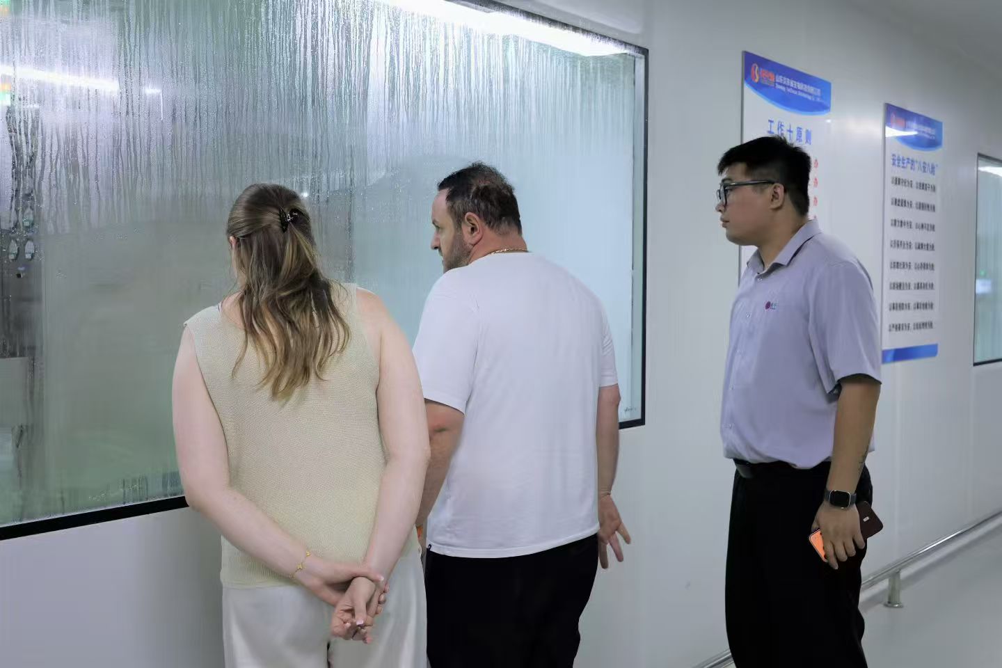 Client viewing Zuoning production room through glass window